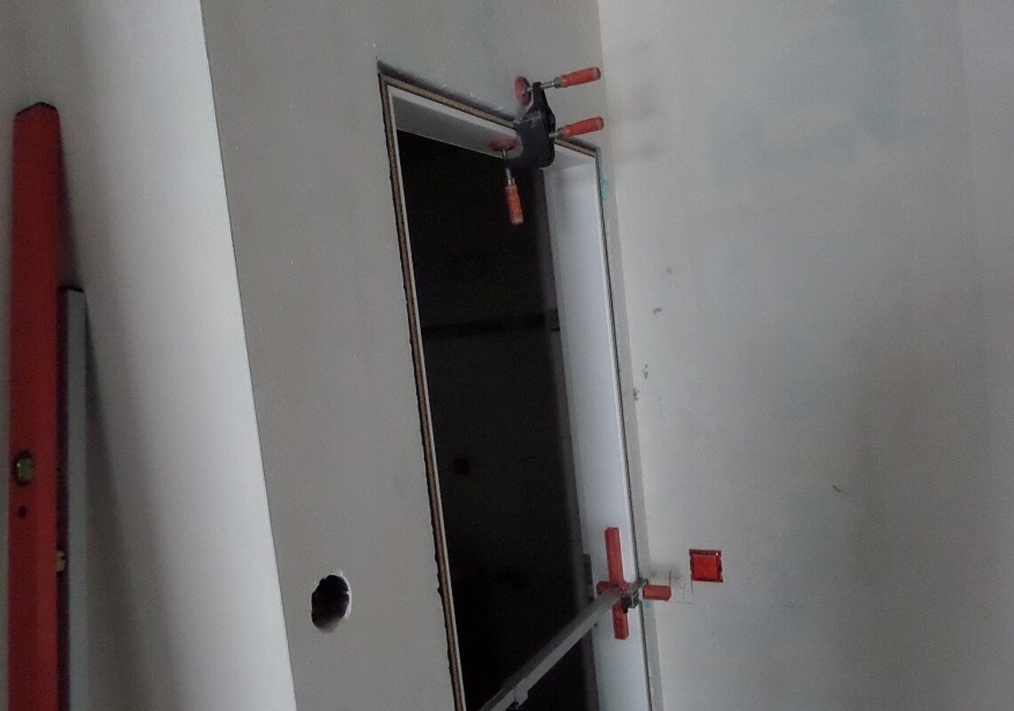 Einbau einer Türzarge, zur Verbesserung des Schallschutzes wird der Abstand zwischen der Türzarge und der Wand mit Schallschutzschaum ausgefüllt