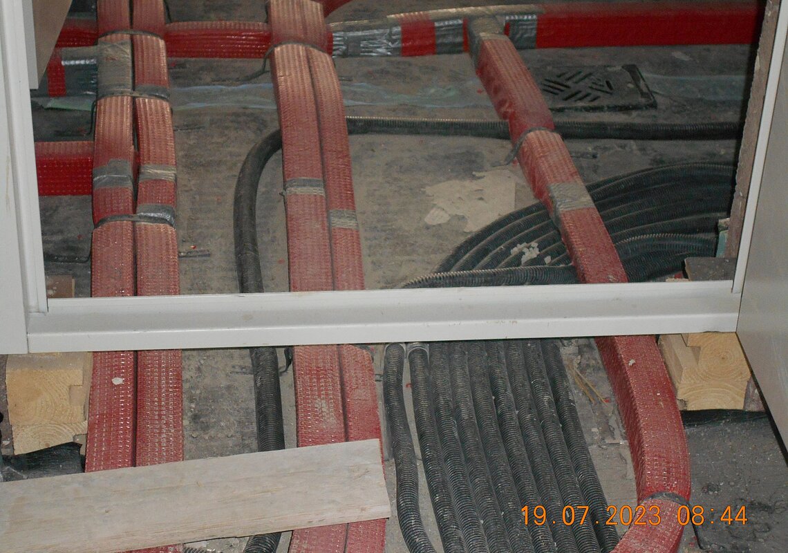 Leitungen und Leerrohre auf dem Boden des Heizraums, die Untermauerung der Stahltüre ist noch nicht ausgeführt